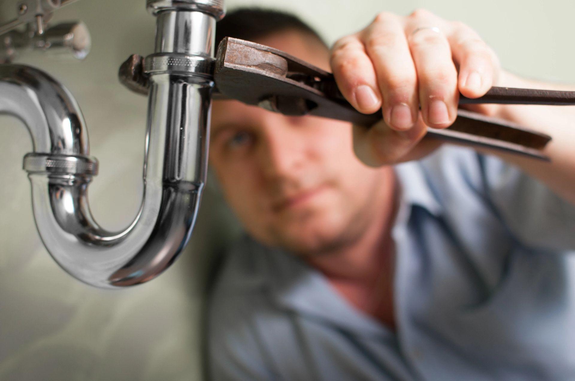 Plumber working under a sink with a pipe wrench